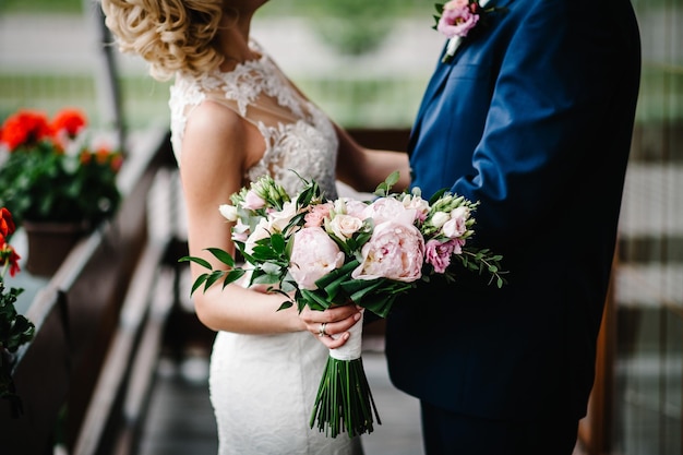 La novia y el novio besando a los recién casados con un ramo de novia de pie en la ceremonia de boda al aire libre Primera reunión en el patio trasero