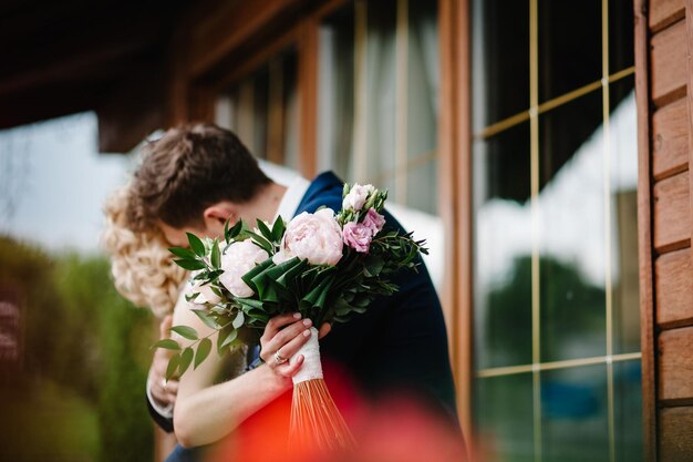 Foto la novia y el novio besando a los recién casados con un ramo de novia de pie en la ceremonia de boda al aire libre primera reunión en el patio trasero