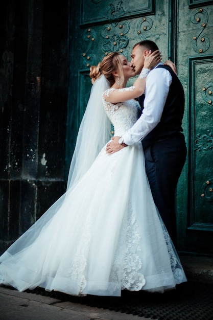 La novia y el novio caminan juntos en el parque. Encantadora novia con un vestido blanco, el novio está vestido con un elegante traje oscuro.