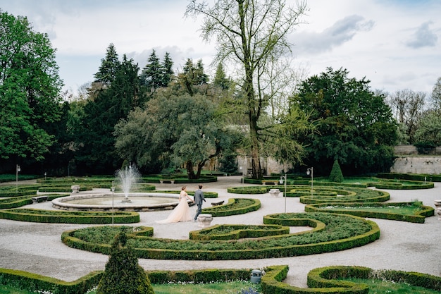 La novia y el novio caminan de la mano en un hermoso parque en Italia