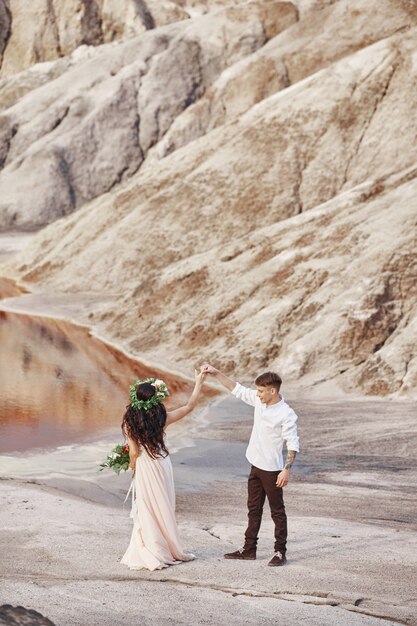 La novia y el novio caminan por las montañas rojas, escena fabulosa. Pareja enamorada