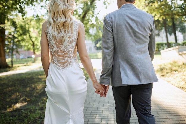 La novia y el novio caminan en la plaza verde.