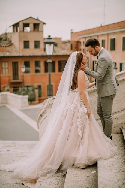 Novia y el novio caminando al aire libre en la Plaza de España y Trinita &#39;dei Monti en Roma, Italia