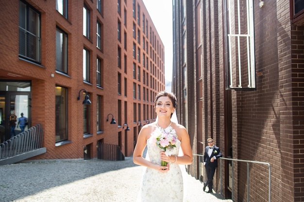 Novia y el novio caminando en la ciudad, día de la boda, matrimonio. Novia y novio en urbano. Joven pareja en el día de la boda.