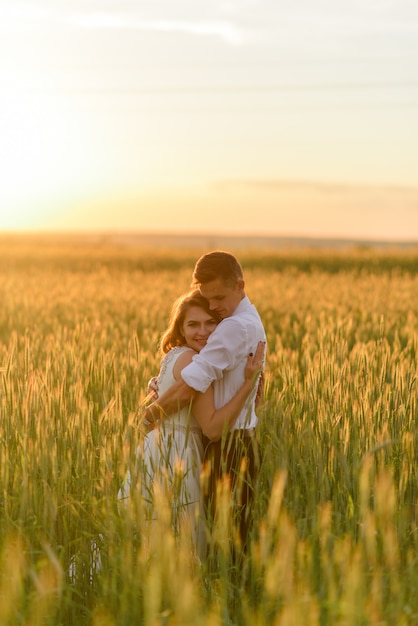 Novia y el novio en un campo de trigo. Una pareja se abraza durante el atardecer.