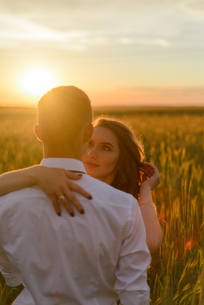 Novia y el novio en un campo de trigo. Una pareja se abraza durante el atardecer.