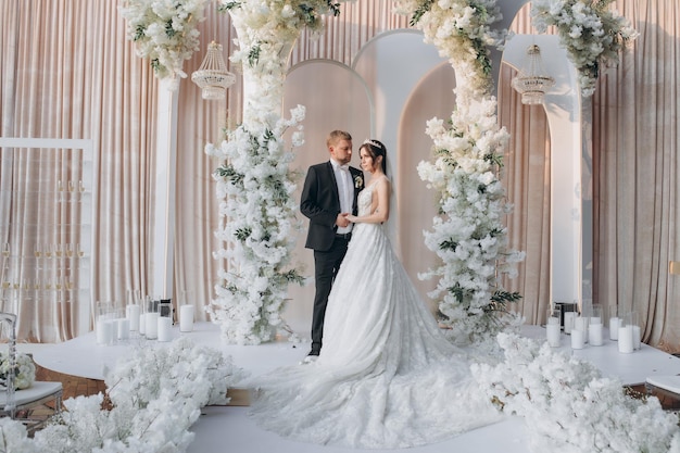 Novia y novio cerca del arco de la boda