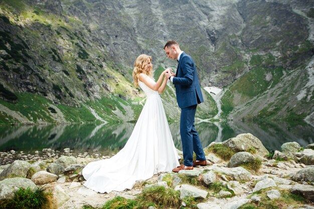 La novia y el novio cerca del lago en las montañas