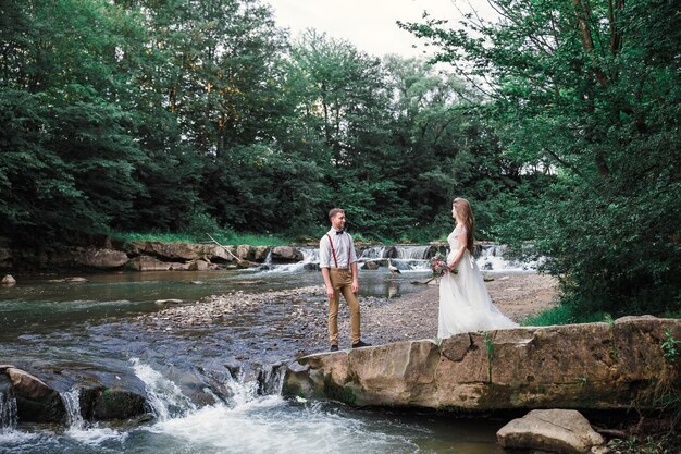 Novia y novio cerca del río de la montaña