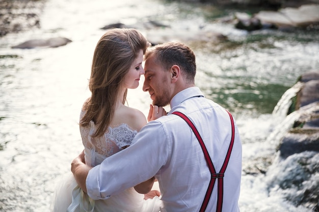 Novia y novio cerca del río de la montaña