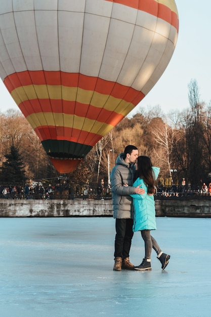 La novia y el novio en el contexto de un lago congelado y un globo volando en un parque de la ciudad.