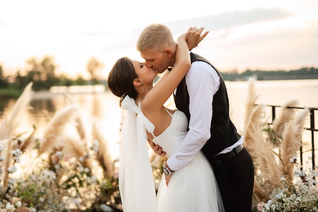 Novia y novio contra el telón de fondo de una puesta de sol amarilla