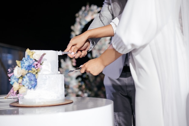 La novia y el novio cortan el pastel de bodas