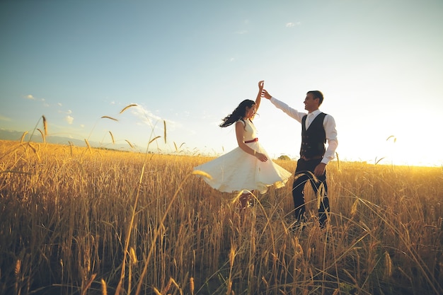 La novia y el novio se dan la mano bailando en el parque.