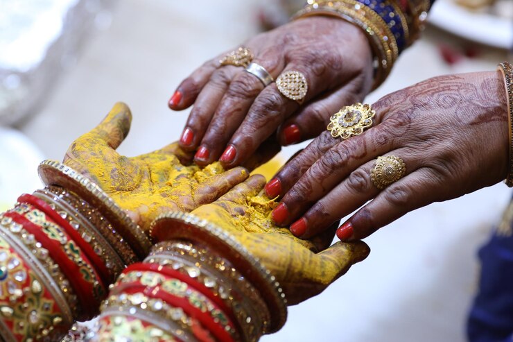 Una novia y un novio se dan la mano con las manos de una novia.