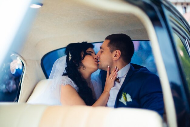 Novia y el novio dentro de un coche clásico. Son felices.