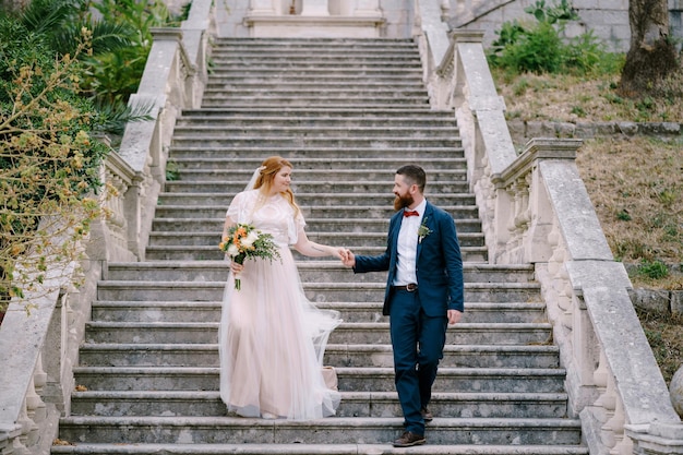 La novia y el novio descienden los pasos tomados de la mano