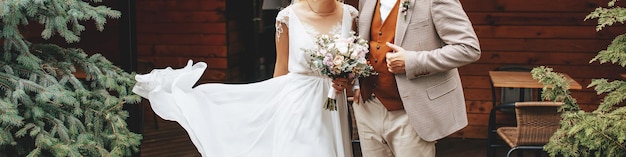 La novia y el novio el día de la boda se abrazan y muestran amor con un ramo de flores rosas