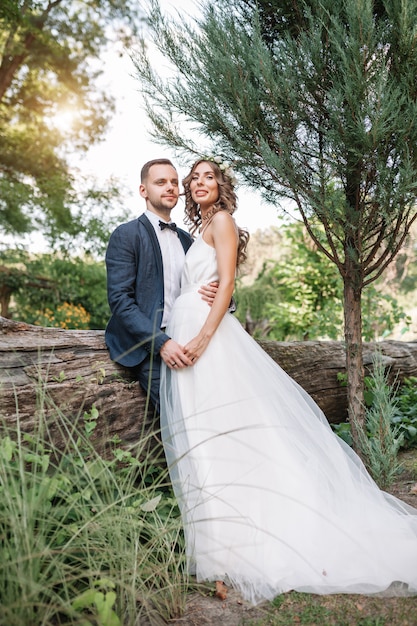 Novia y el novio en el día de la boda caminando al aire libre en la naturaleza de verano