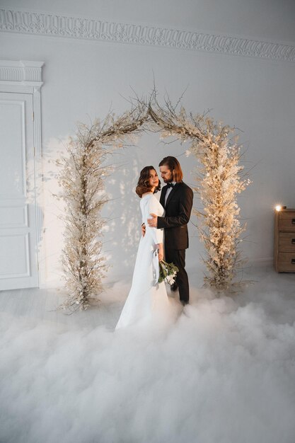 novia y novio en el día de su boda cerca del arco festivo