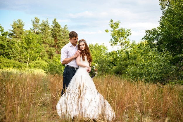 La novia y el novio en las espigas de trigo en el bosque.