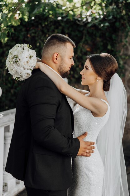 Una novia y un novio se están abrazando en un traje negro y un vestido blanco