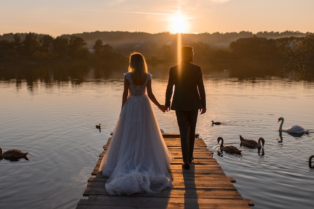 La novia y el novio están atrás al atardecer.