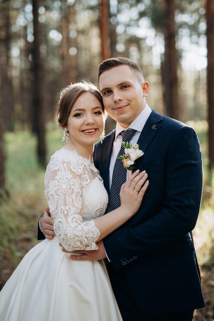 La novia y el novio están caminando en un bosque de pinos en un día brillante