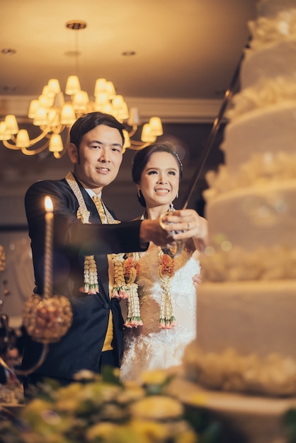 La novia y el novio están cortando la torta para la celebración el día de su boda