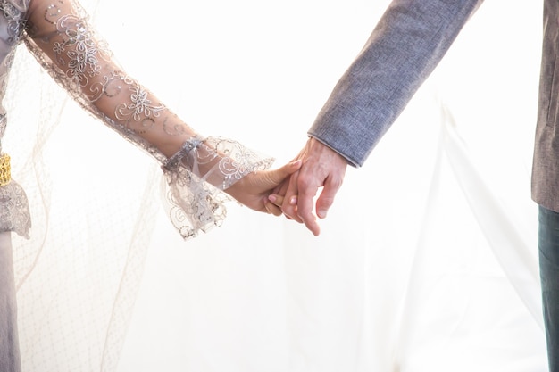 Foto una novia y un novio se están juntando de la mano en el matrimonio