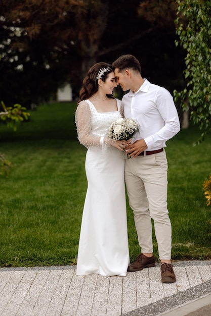 Una novia y un novio están juntos en un camino de grava frente a un árbol.