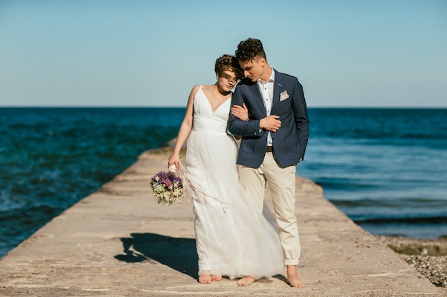 Novia y el novio están de pie en el muelle