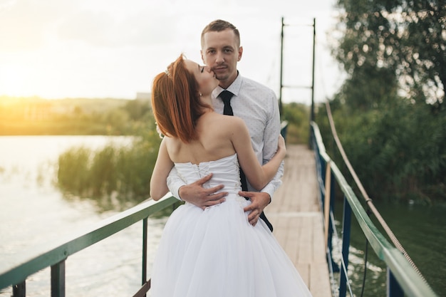 La novia y el novio están de pie en el puente