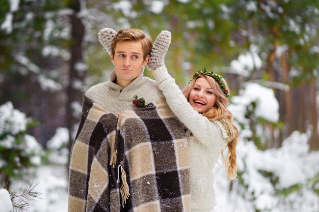 La novia y el novio están sentados en el inicio de sesión en el bosque de invierno. De cerca. Ceremonia de boda de invierno.