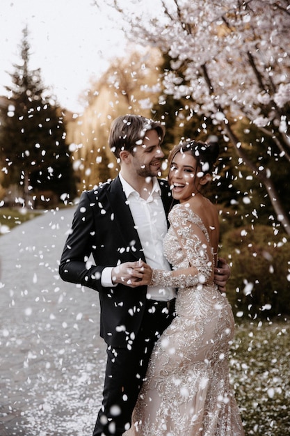 La novia y el novio con estilo cerca del cerezo en flor. Boda en el parque.