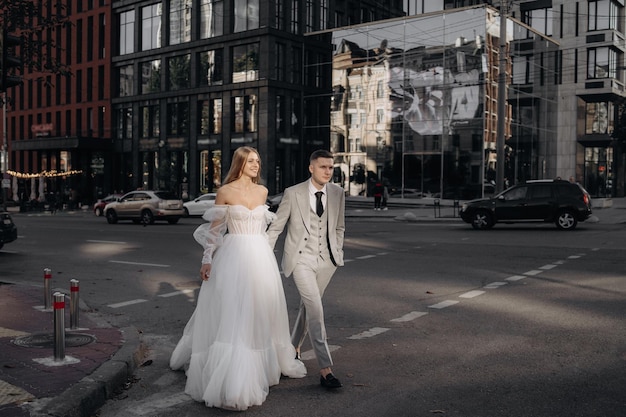 Novia y novio europeos con estilo caminando por la calle de la ciudad La novia con un vestido de moda