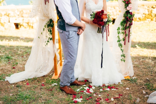 La novia y el novio en la hierba bajo el arco en la boda