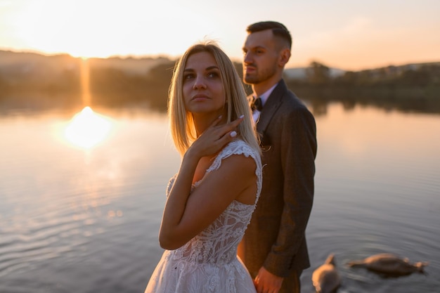 La novia y el novio juntos se encuentran con la puesta de sol.