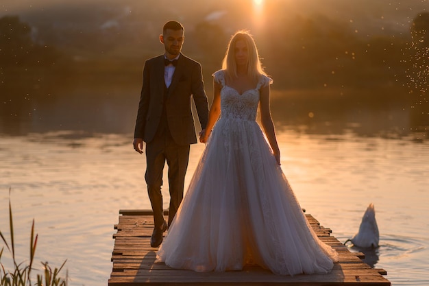 La novia y el novio juntos se encuentran con la puesta de sol.