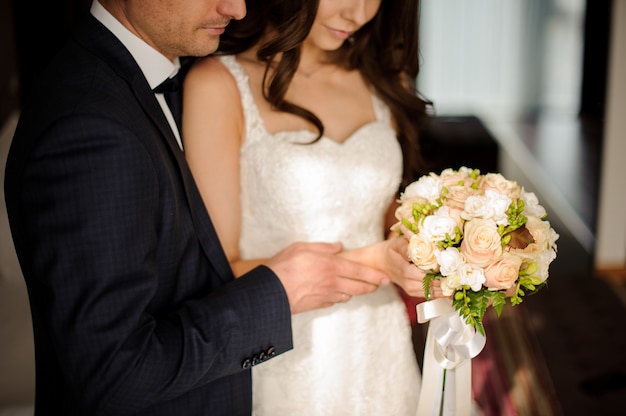 La novia y el novio mirando juntos el ramo de rosas