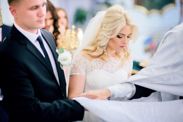 Foto la novia y el novio se paran con coronas ante el sacerdote