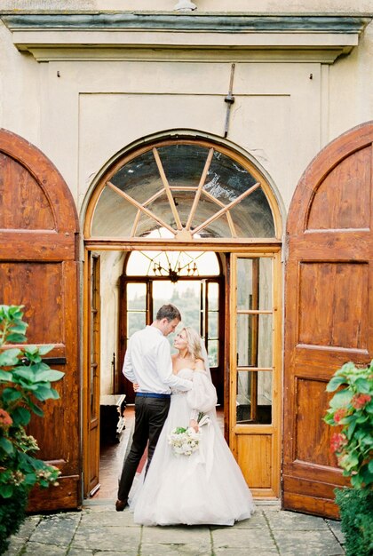 La novia y el novio se paran frente a la puerta de una antigua villa en Florencia Italia