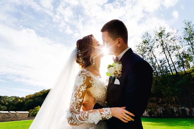 La novia y el novio se paran en un hermoso jardín verde en un cálido día de verano