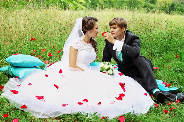 Novia y novio en pétalos de rosa