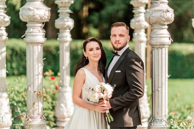 La novia y el novio de pie en un cenador arqueado