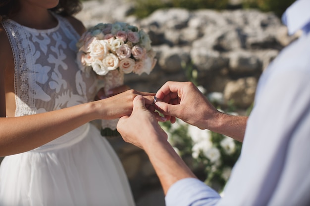 Novia y novio ponen en el dedo un anillo de bodas