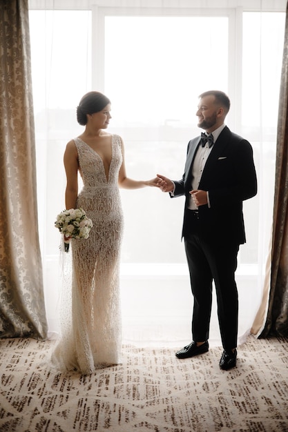 La novia y el novio posan frente a una ventana en el ritz carlton en toronto