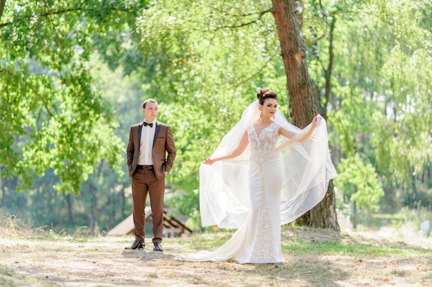 La novia y el novio posando al aire libre frente a la cámara. Centrarse en la novia.