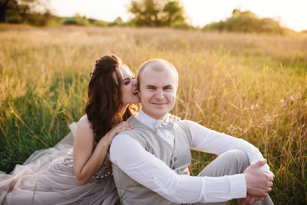 Novia y el novio posando en el campo al atardecer