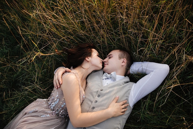 Novia y el novio posando en el campo al atardecer